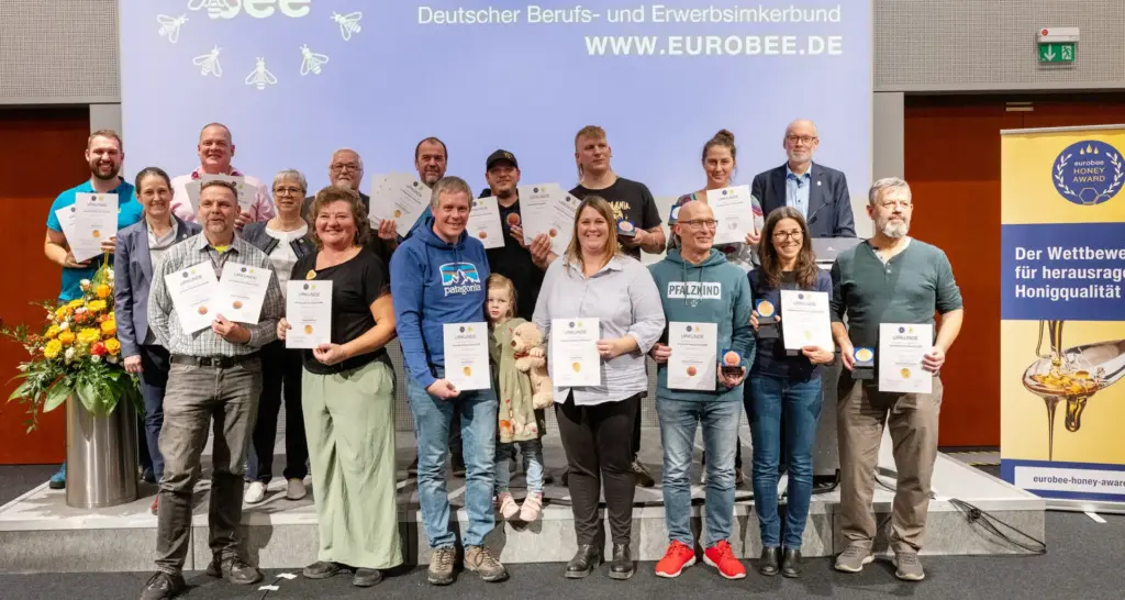 Belohnung für harte Arbeit und größte Sorgfalt: Die strahlenden Sieger des eurobee Honey Awards 2025 mit Urkunden und Medaillen für beste Honigqualität und ausgezeichneten Geschmack. (v.l.n.r. hinten: Johannes Fähnle, Mike Gerdes, Klaus Schmieder, Klaus Ahrens, Harald Aumeier, Martin Müller, Elisabeth Stolarczuk, Dr. Steffen Watzke, mitte: Ursula Lensing, Annette Seehaus-Arnold, vorne: Sven Bestmann, Helena Raff, Kilian und Anna Stumm mit Tochter, Jörg Homuth, Milka Pishmisheva, Oliver Leis). Foto: DBIB/Jan Gutzeit